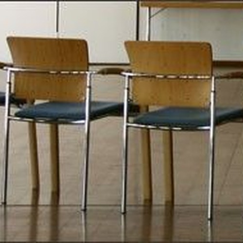 Foto eines Tagungsraums mit leerem Stuhlkreis als Symbol für Arbeitskreise.
